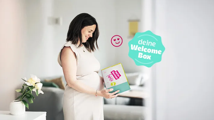 Deine Welcome Box. Schwangere Frau hält die Welcome Box in den Händen.